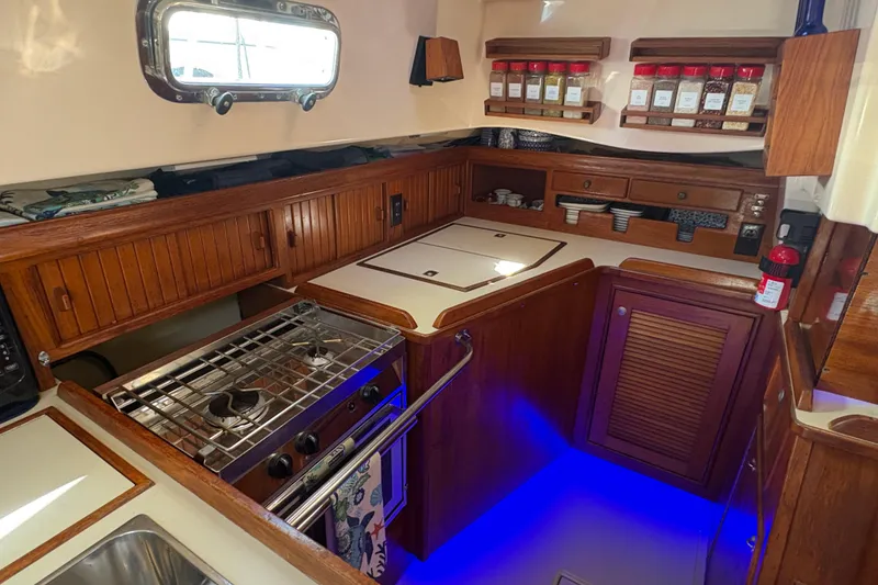 Slide: The Image of 1995 Island Packet 40 yacht kitchen with wooden cabinetry, stove, and spice rack. - 35