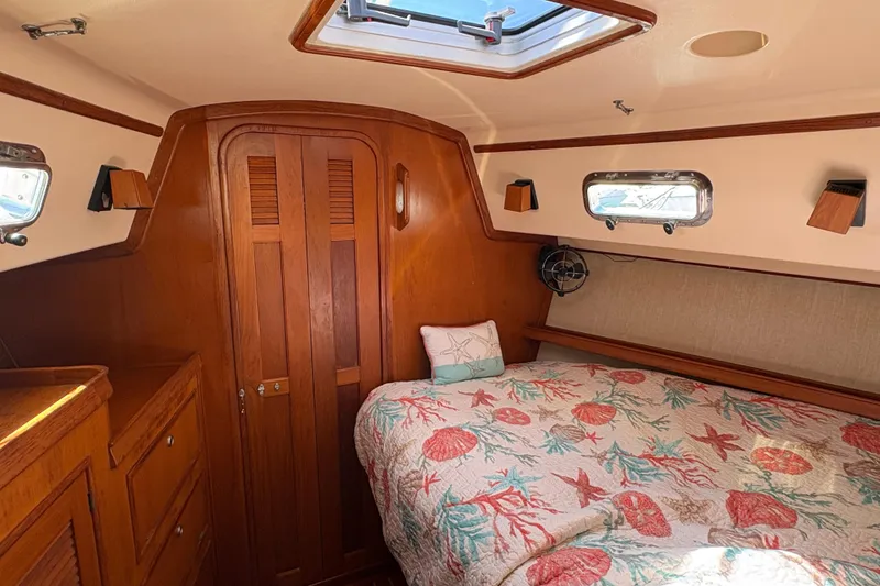 Slide: The Image of Forward cabin of a 1995 Island Packet 40 sailboat with nautical-themed bedding. - 43