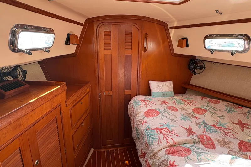 Slide: The Image of Cozy cabin interior of a 1995 Island Packet 40 sailboat with nautical-themed bedding. - 44