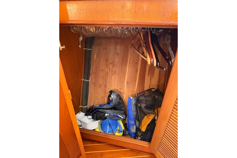 Slide: The Image of Wooden closet interior on 1995 Island Packet 40 yacht, with hangers and stored gear. - 54
