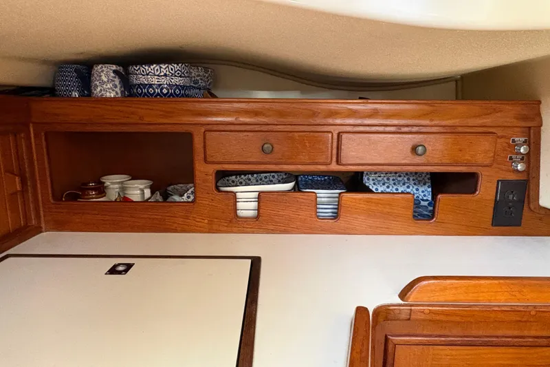 Slide: The Image of Wooden cabinet with blue-patterned dishes in a 1995 Island Packet 40 sailboat interior. - 55