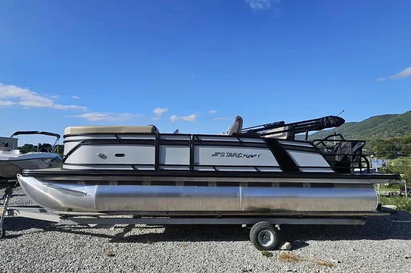 Slide: The Image of 2026 Starcraft EXS 3 Q DH pontoon boat on trailer, under clear blue sky. - 6