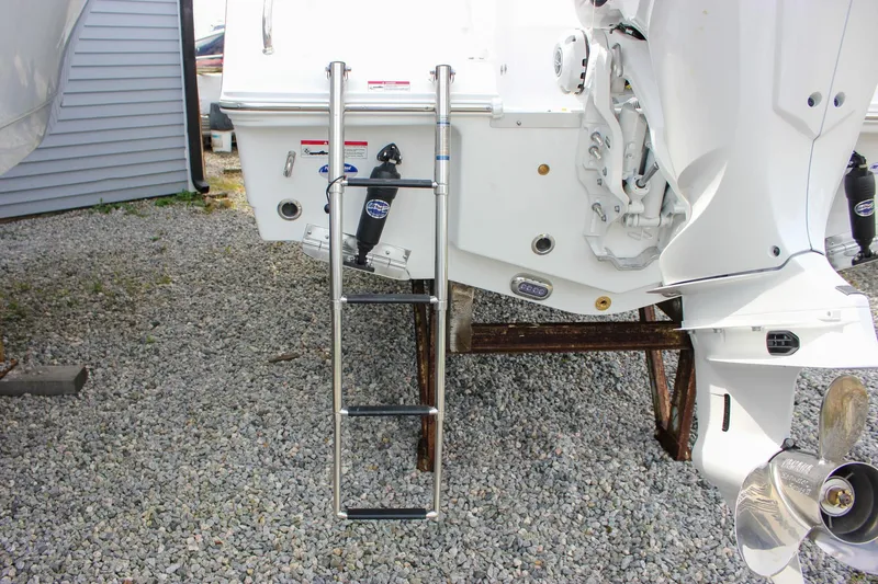 Slide: The Image of 2026 Sea Hunt Ultra 235 SE boat with ladder and outboard motor on gravel. - 11