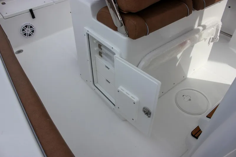 Slide: The Image of 2026 Sea Hunt Ultra 235 SE boat interior with storage compartment and brown seating. - 23