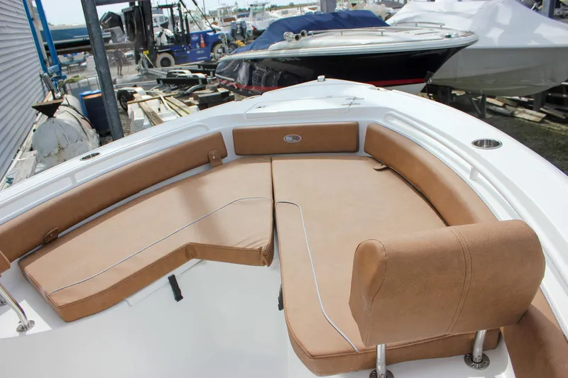 Slide: The Image of 2026 Sea Hunt Ultra 235 SE boat with tan cushioned seating in a marina setting. - 43