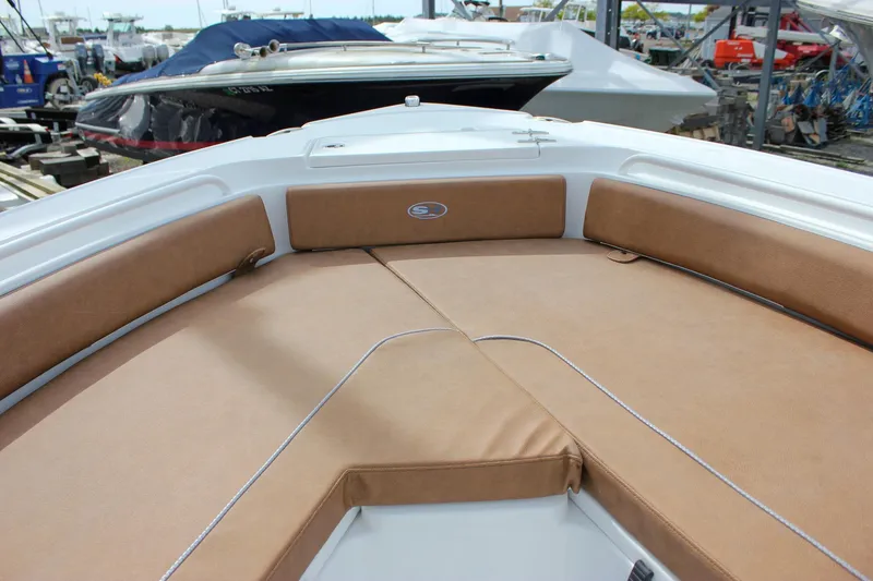 Slide: The Image of 2026 Sea Hunt Ultra 235 SE boat with tan cushioned seating in a marina. - 44