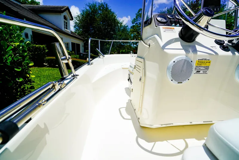 Slide: The Image of 2016 Boston Whaler 170 Montauk boat interior with steering console, near a house and greenery. - 11