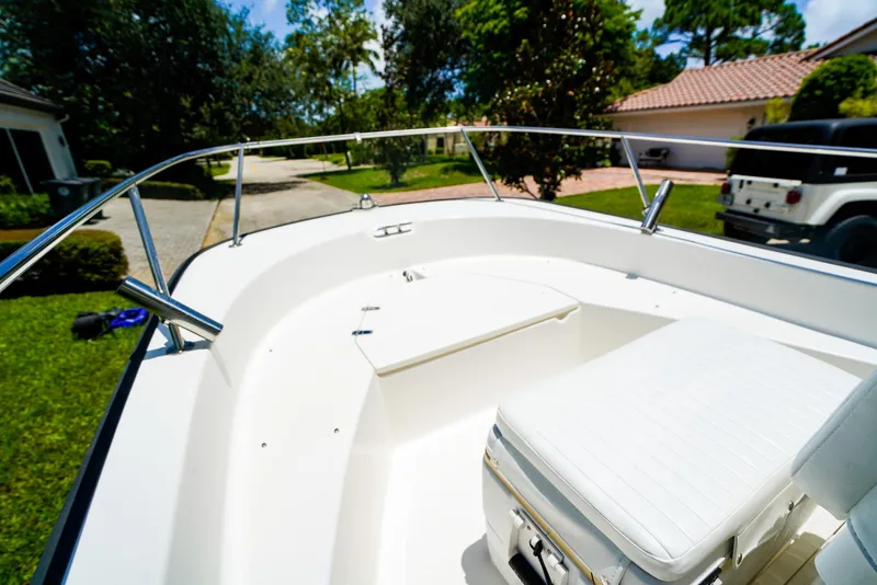 Slide: The Image of 2016 Boston Whaler 170 Montauk boat interior with white seating and railing, parked outdoors. - 13