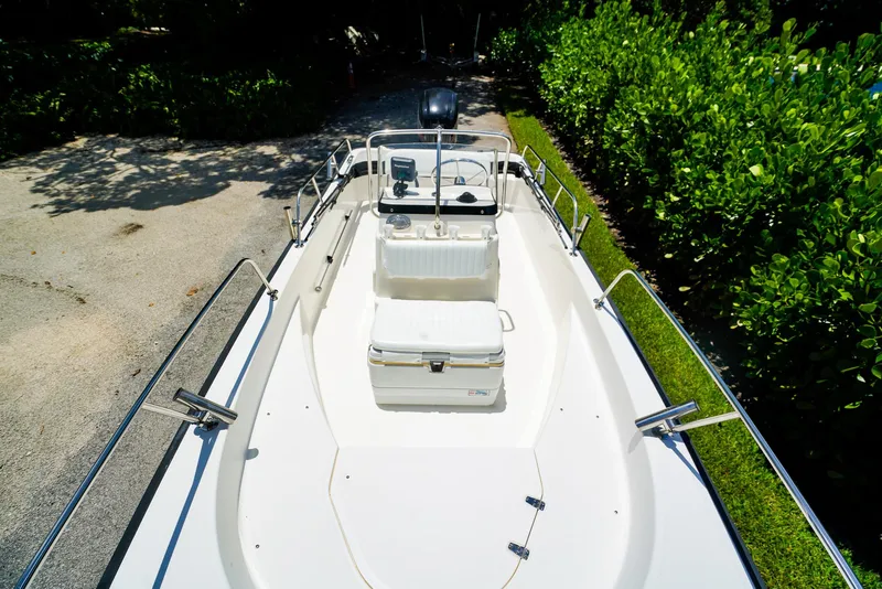 Slide: The Image of 2016 Boston Whaler 170 Montauk boat, white interior, parked on a sunny driveway. - 16