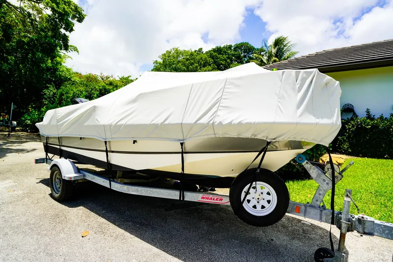 Slide: The Image of 2016 Boston Whaler 170 Montauk boat covered on trailer, parked outdoors. - 22