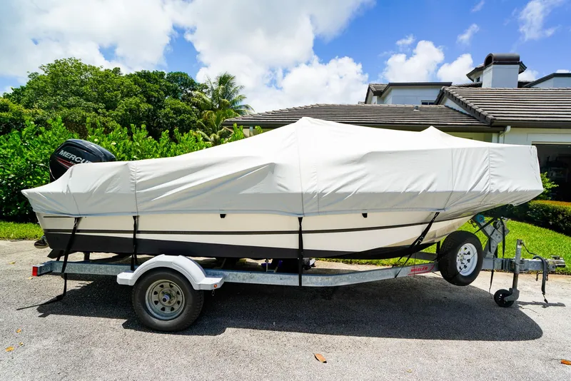 Slide: The Image of 2016 Boston Whaler 170 Montauk boat covered on trailer, parked outdoors. - 23