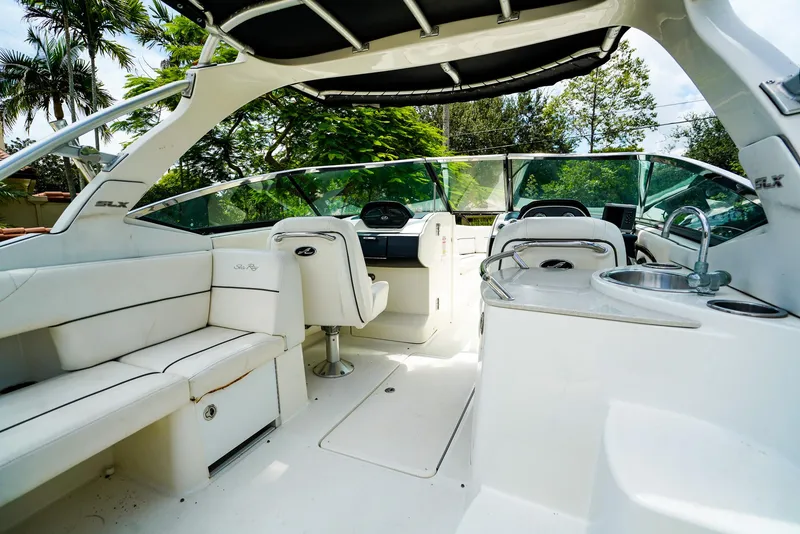 Slide: The Image of 2010 Sea Ray 270 SLX boat interior with white seating, helm, and sink under canopy. - 10