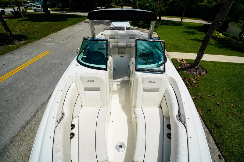 Slide: The Image of 2010 Sea Ray 270 SLX boat with white seating, parked on a residential street. - 25