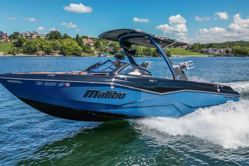 The Image of 2022 Malibu Wakesetter 25 LSV boat cruising on a scenic lake. - 0