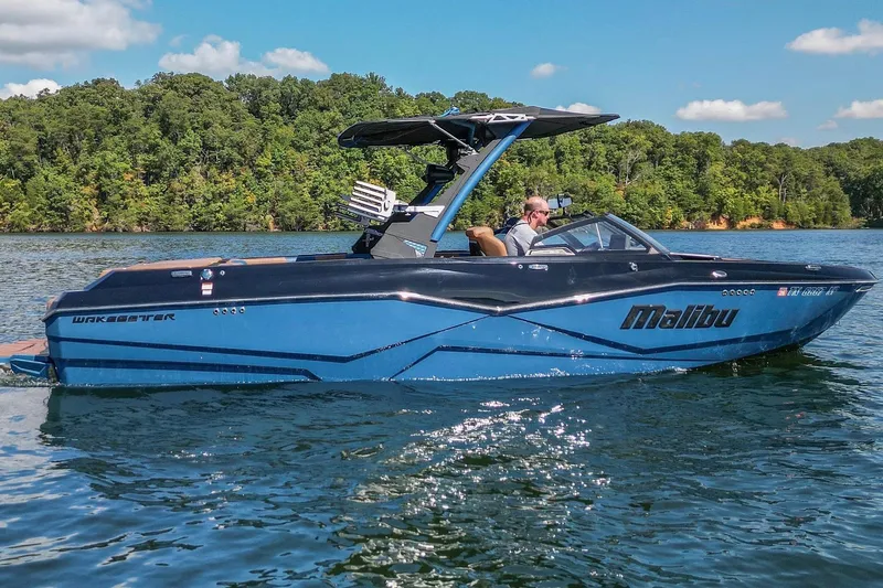 Slide: The Image of 2022 Malibu Wakesetter 25 LSV boat cruising on a scenic lake. - 2