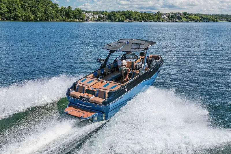 Slide: The Image of 2022 Malibu Wakesetter 25 LSV cruising on a scenic lake with lush greenery. - 8