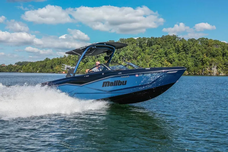 Slide: The Image of 2022 Malibu Wakesetter 25 LSV cruising on a scenic lake under a clear blue sky. - 9