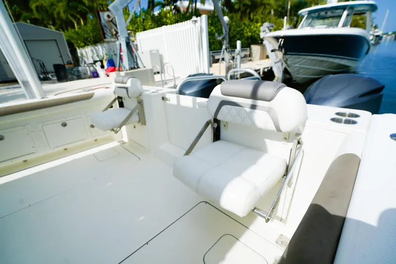 Slide: The Image of 2018 World Cat 320 CC boat interior with white seating and docked boats in background. - 10