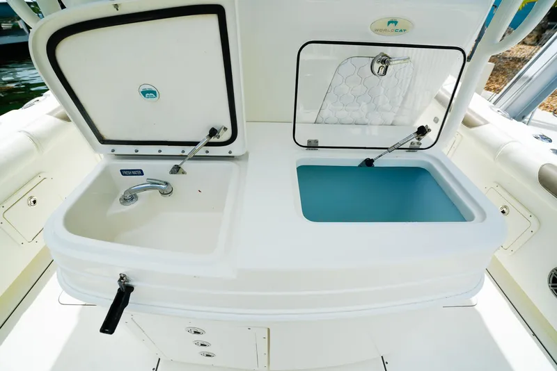 Slide: The Image of 2018 World Cat 320 CC boat sink and storage compartments open on deck. - 15