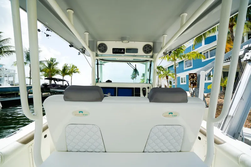 Slide: The Image of 2018 World Cat 320 CC boat interior with helm, palm trees, and waterfront view. - 18