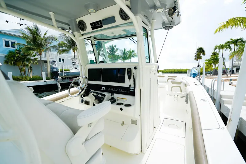 Slide: The Image of 2018 World Cat 320 CC boat interior with steering wheel and control panel, docked near palm trees. - 20