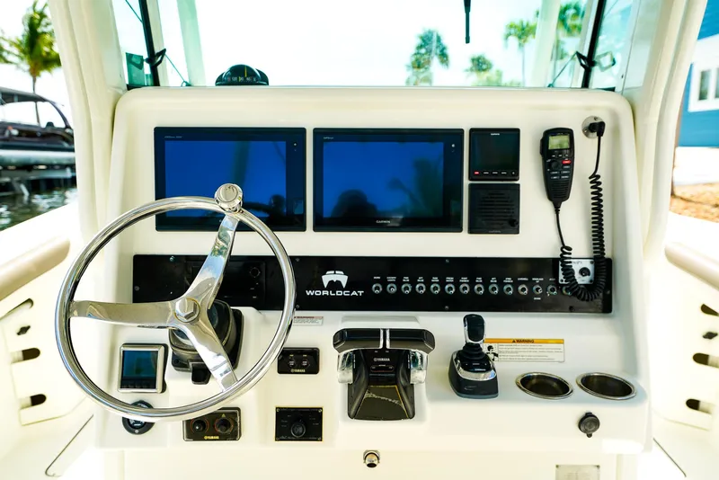 Slide: The Image of Control panel of 2018 World Cat 320 CC boat with steering wheel and navigation screens. - 24