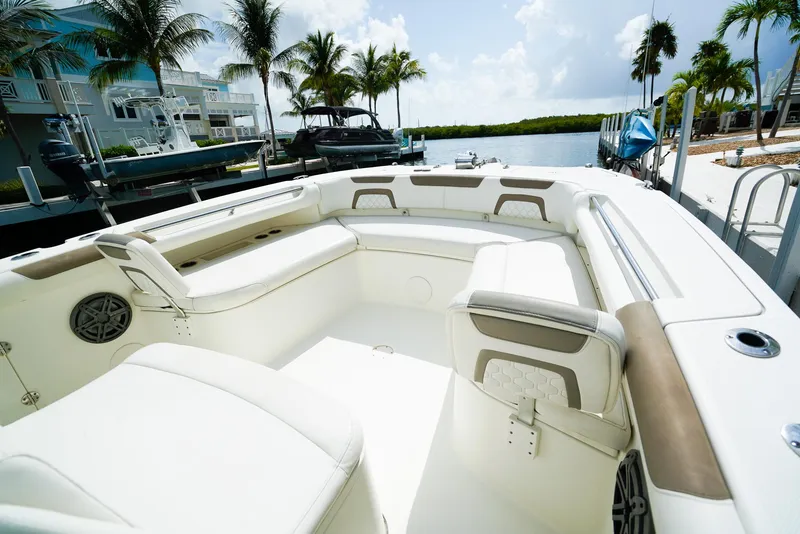 Slide: The Image of 2018 World Cat 320 CC boat interior with white seating, docked near palm trees. - 31