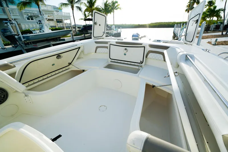 Slide: The Image of 2018 World Cat 320 CC boat interior with open storage compartments, docked near palm trees. - 32