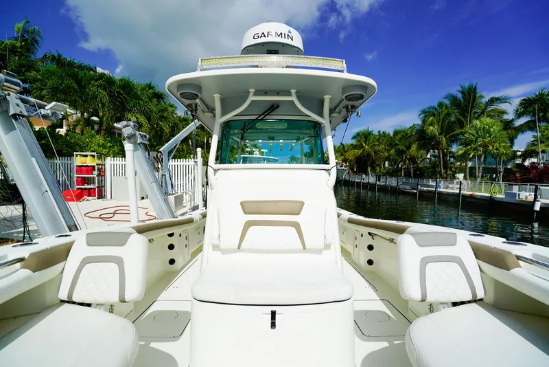 Slide: The Image of 2018 World Cat 320 CC boat interior with seating, docked near palm trees and waterway. - 34