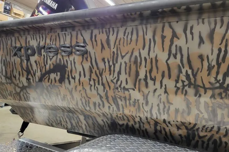 Slide: The Image of Camouflage-patterned 2026 Xpress H20B Bay boat with Yamaha motor in a showroom. - 6