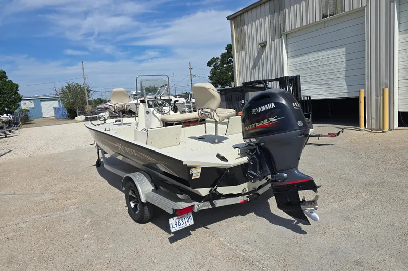 Slide: The Image of 2017 Xpress H20B Bay boat with Yamaha engine on trailer, parked outside a warehouse. - 5