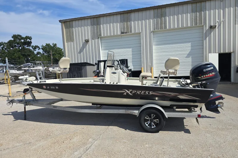 Slide: The Image of 2017 Xpress H20B Bay boat with Yamaha engine on trailer, parked outside a warehouse. - 6