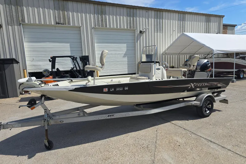 Slide: The Image of 2017 Xpress H20B Bay boat on trailer, parked outside a warehouse. - 7