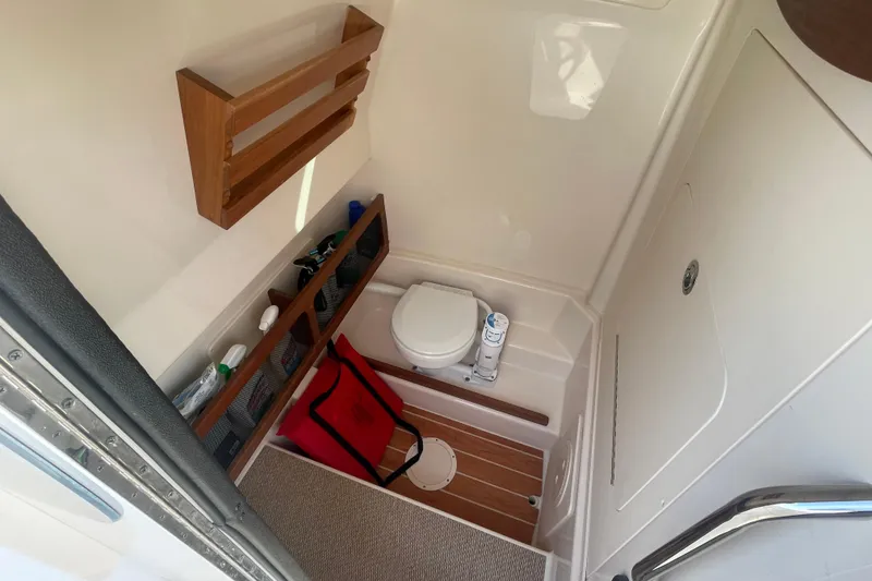 Slide: The Image of 2021 Grady-White Canyon 271 boat interior with compact bathroom and storage shelves. - 19