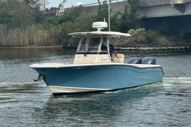 Slide: The Image of 2021 Grady-White Canyon 271 boat cruising on a calm river near a bridge. - 2