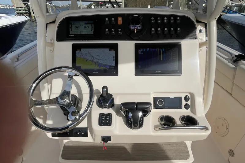 Slide: The Image of 2021 Grady-White Canyon 271 boat dashboard with steering wheel and navigation screens. - 22