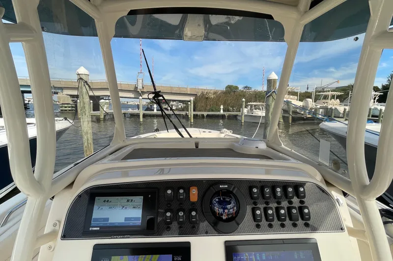 Slide: The Image of 2021 Grady-White Canyon 271 boat dashboard with navigation controls at a marina. - 29