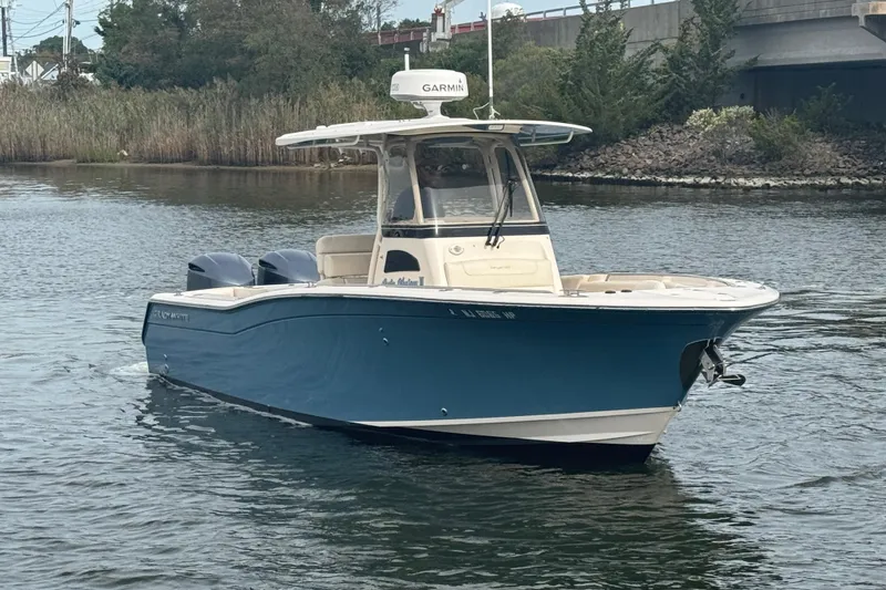 Slide: The Image of 2021 Grady-White Canyon 271 boat on calm water, featuring a sleek blue hull. - 5
