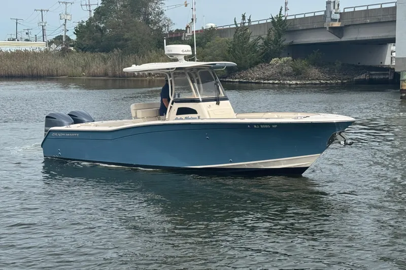 Slide: The Image of 2021 Grady-White Canyon 271 boat on water near a bridge, featuring a sleek blue design. - 7