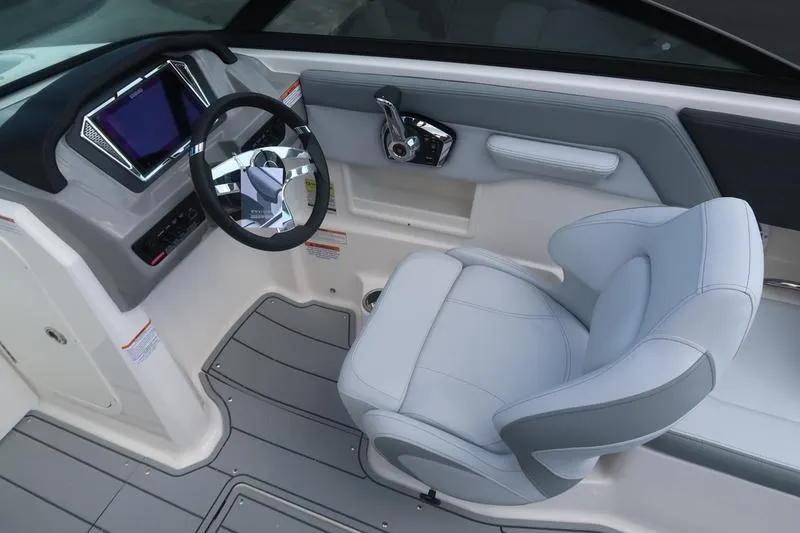 Slide: The Image of Interior view of 2026 Chaparral 23 SSi boat, featuring safety labels and a drain. - 49