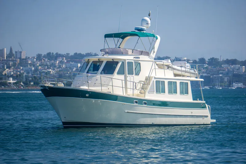 Slide: The Image of 2008 North Pacific 43 Pilothouse yacht on calm water with cityscape background. - 2