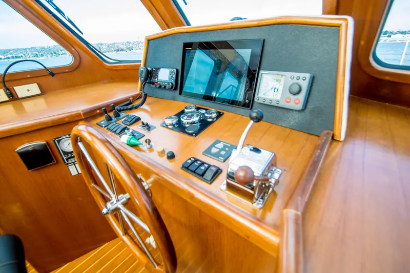 Slide: The Image of Pilothouse interior of 2008 North Pacific 43, featuring navigation controls and wooden steering wheel. - 22