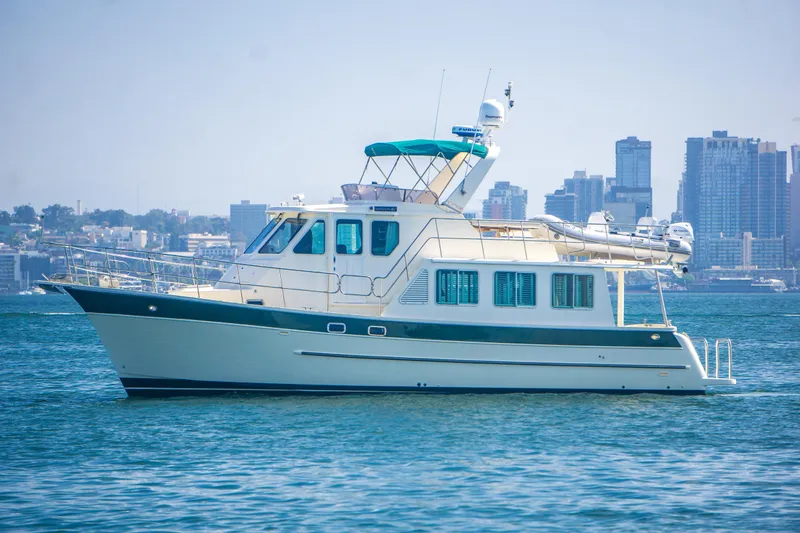 Slide: The Image of 2008 North Pacific 43 Pilothouse yacht on water with city skyline background. - 3