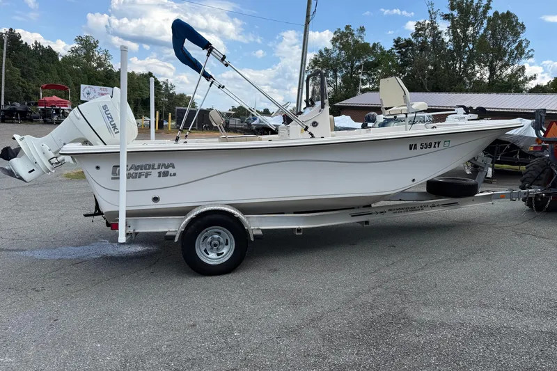 Slide: The Image of 2020 Carolina Skiff 19 LS boat on trailer with Suzuki outboard motor, parked outdoors. - 1