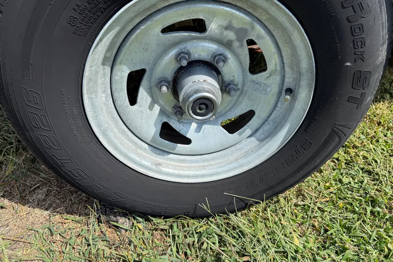 Slide: The Image of Close-up of a 2020 Carolina Skiff 19 LS trailer wheel on grass. - 12