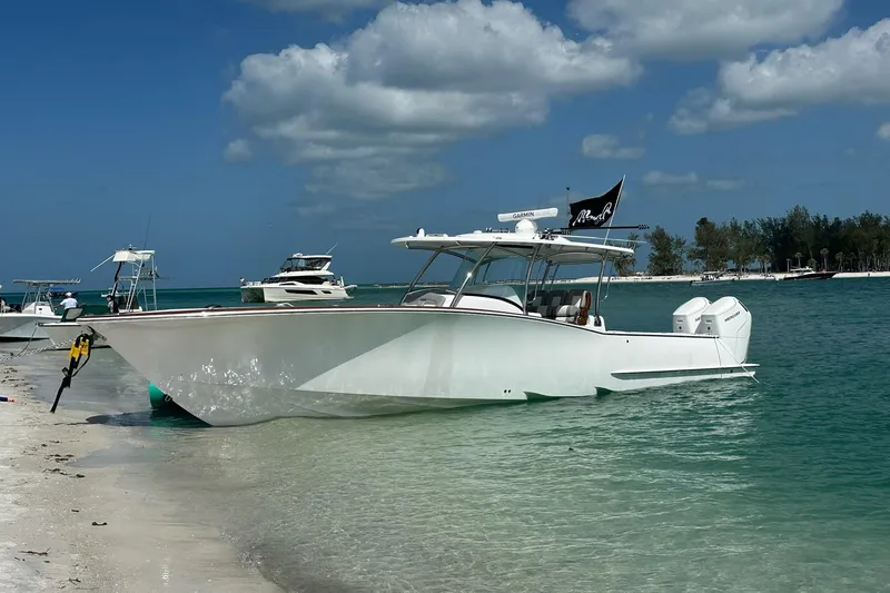 The Image of 2026 Mag Bay 38 CC boat anchored on a sandy beach with clear blue water. - 0