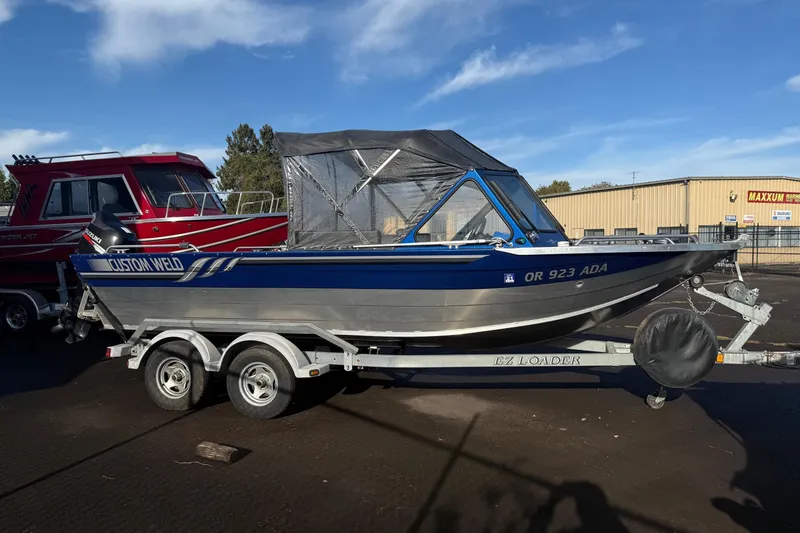 Slide: The Image of 2006 Custom Weld Cobra OB boat on trailer, blue and silver design, parked outdoors. - 3