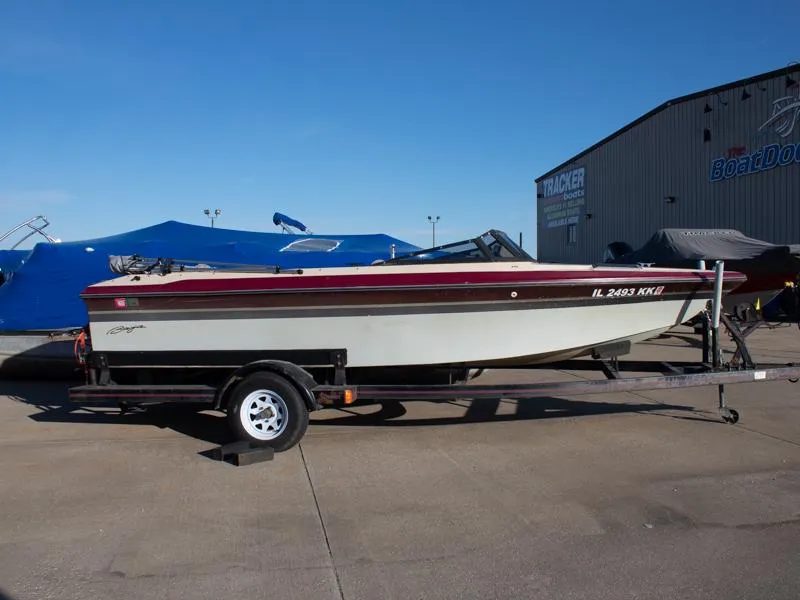 Slide: The Image of 1987 Baja 190 Sport boat on trailer, parked outdoors near a warehouse. - 0