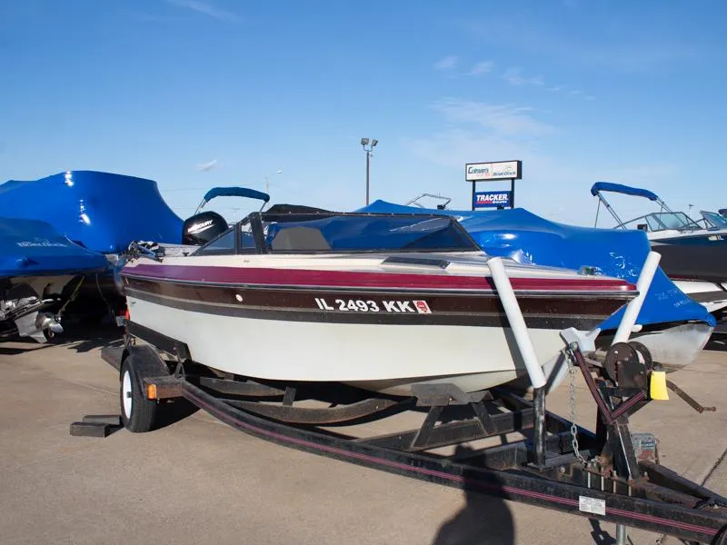Slide: The Image of 1987 Baja 190 Sport boat on trailer, parked outdoors under clear blue sky. - 2