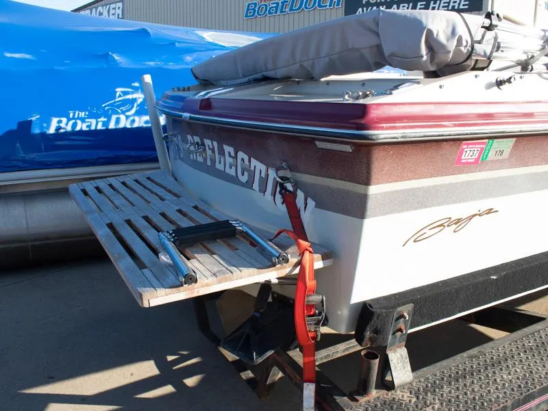 Slide: The Image of 1987 Baja 190 Sport boat with wooden swim platform, parked at a marina. - 5